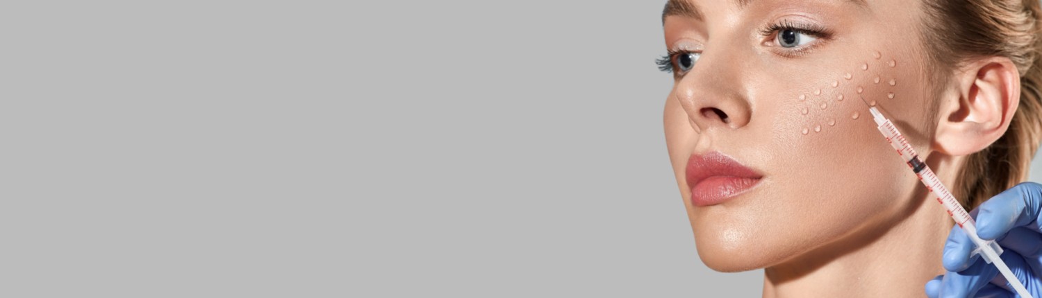 Biorevitalization procedure. Pretty woman while beauty injections with hyaluronic acid for smoothing of mimic wrinkles around eyes, over grey background with space for text